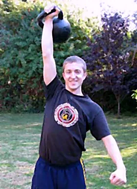 Anton Summers pressing a kettlebell overhead outdoors