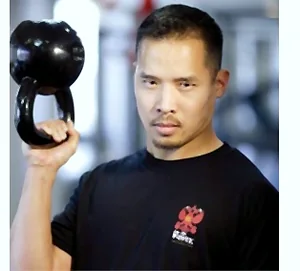 Dr. Mark Cheng holding a kettlebell in the rack position
