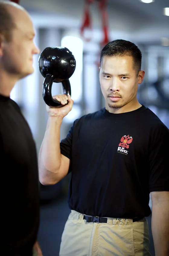 Dr. Mark Cheng correcting a student's kettlebell rack position during a private session